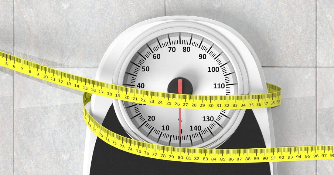 Analog bathroom scale with tape measure symbolizing weight loss.